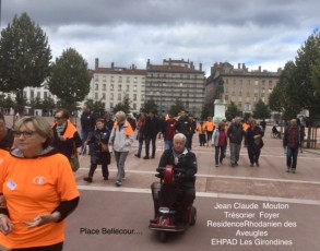 Jean-Claude MOUTON sur son scooter électrique, au milieu des marcheurs sur la place.